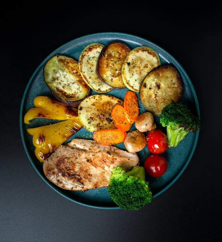 Overhead view of many white and cream plates and bowls of different sizes arranged on a pale wooden surface