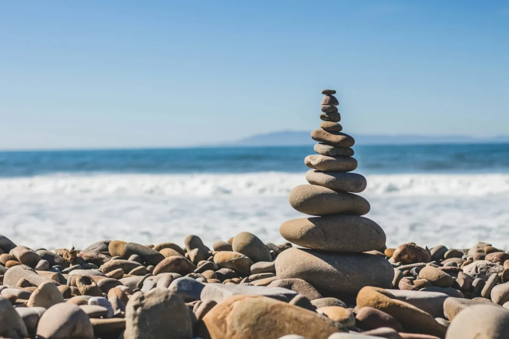 Stack of smooth balanced stones on a pebble beach with ocean waves behind