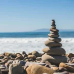 Stack of smooth balanced stones on a pebble beach with ocean waves behind