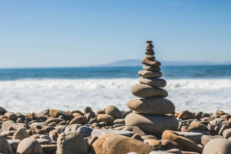 Stack of smooth balanced stones on a pebble beach with ocean waves behind