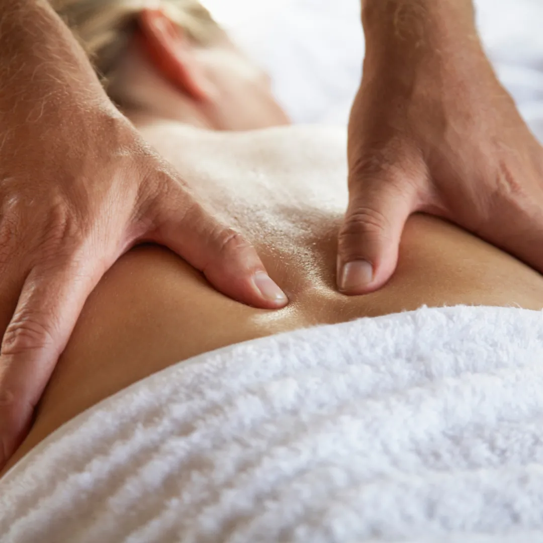 Close-up of hands performing energy healing or therapeutic touch on a person’s back.