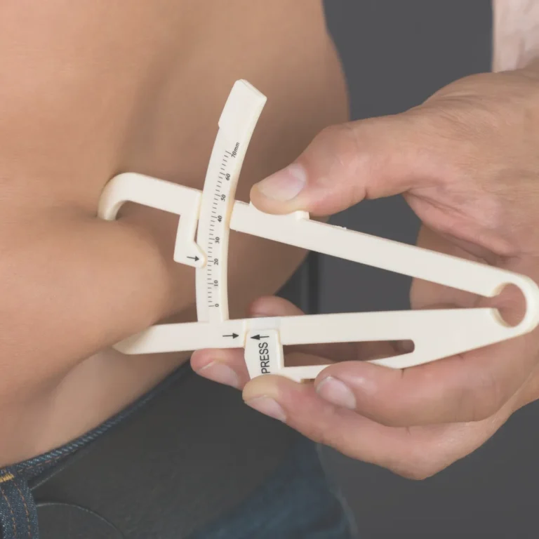 Close-up of a person using body fat calipers on their waist to estimate their body composition.