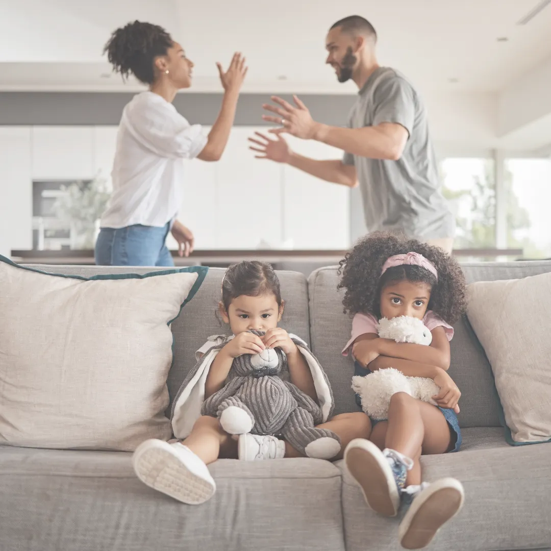 Two children distressed on a couch as parents argue in the background, representing developmental trauma.