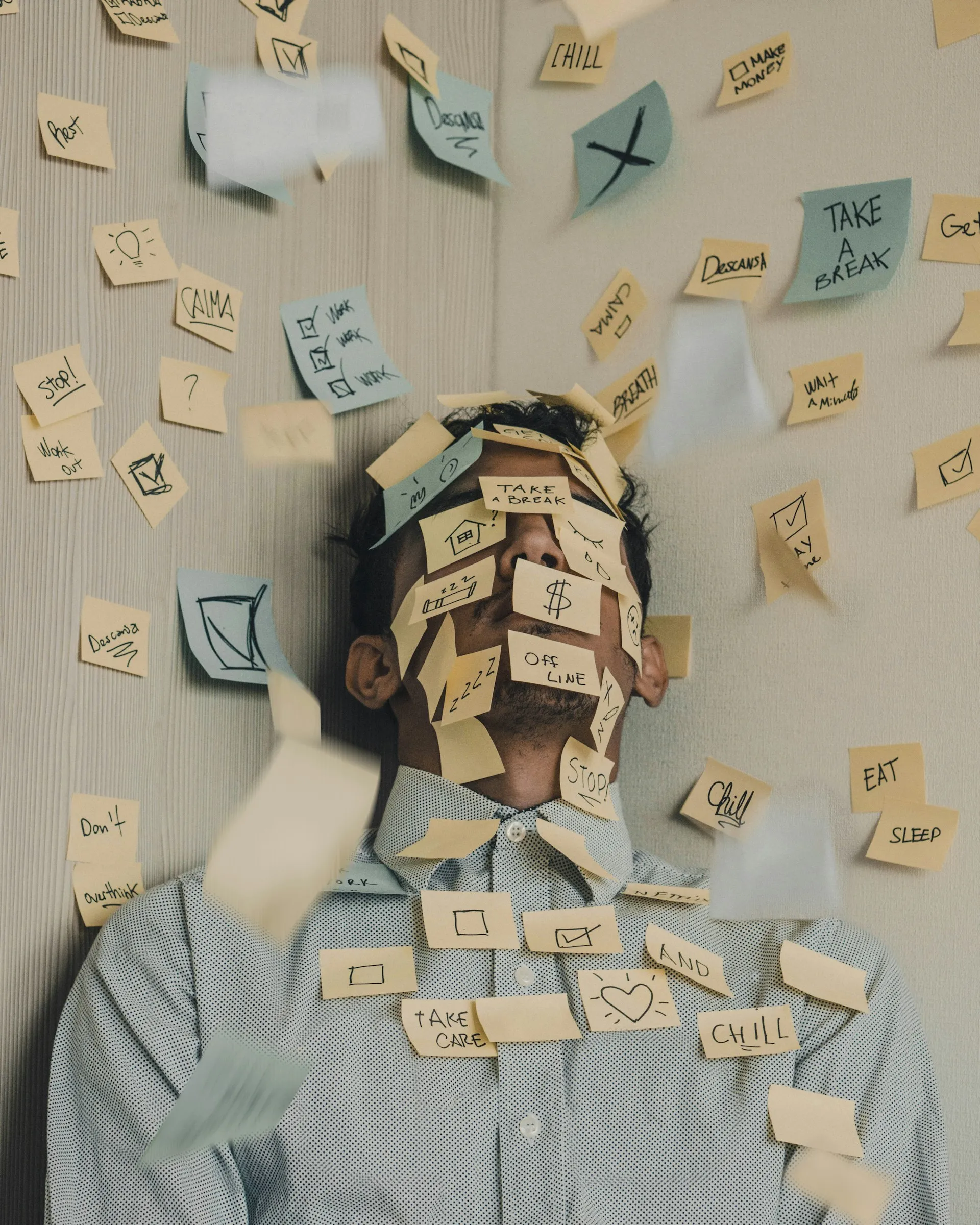 Stressed corporate professional covered in sticky notes signifying chronic multitasking and cognitive information overload.