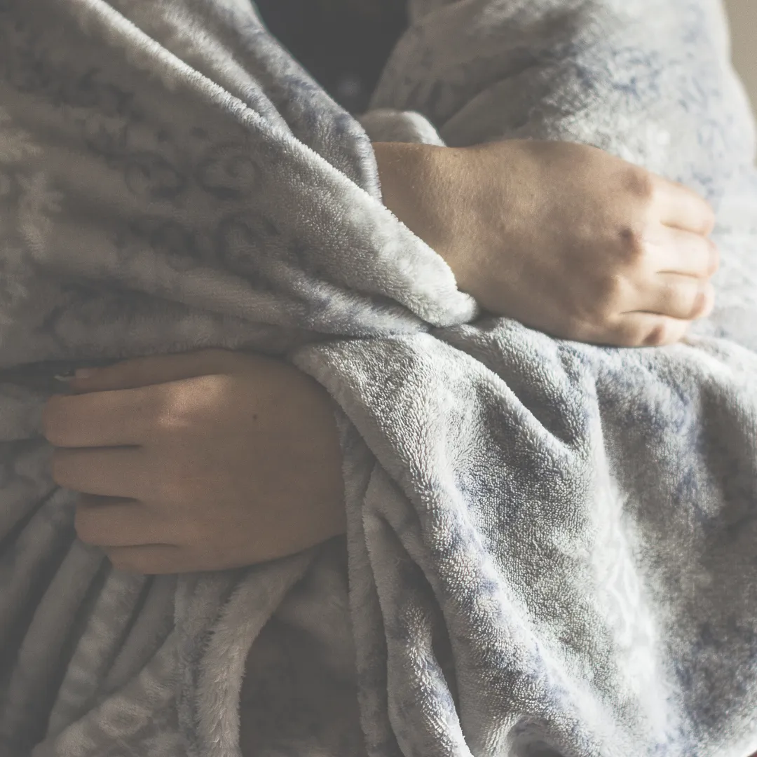 A close-up of a person wrapped snugly in a warm, soft blanket, symbolizing the importance of recovery and rewarming after a cold plunge.