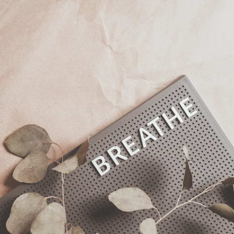 A letter board spelling out the word BREATHE, decorated with calming eucalyptus leaves, representing the core practice of conscious breathing for self-awareness and wellness.