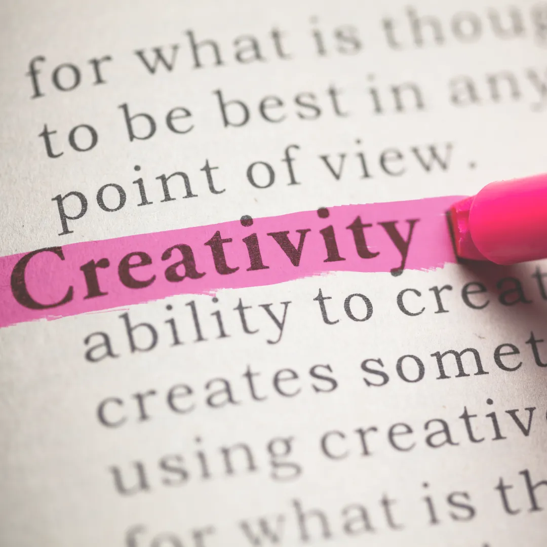 A close-up of a book page with the word 'Creativity' highlighted in pink, emphasizing its definition.