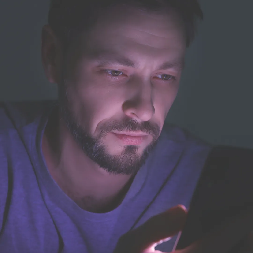 Man engrossed in his smartphone late at night, illustrating the impact of dopamine cycles in screen addiction psychology.