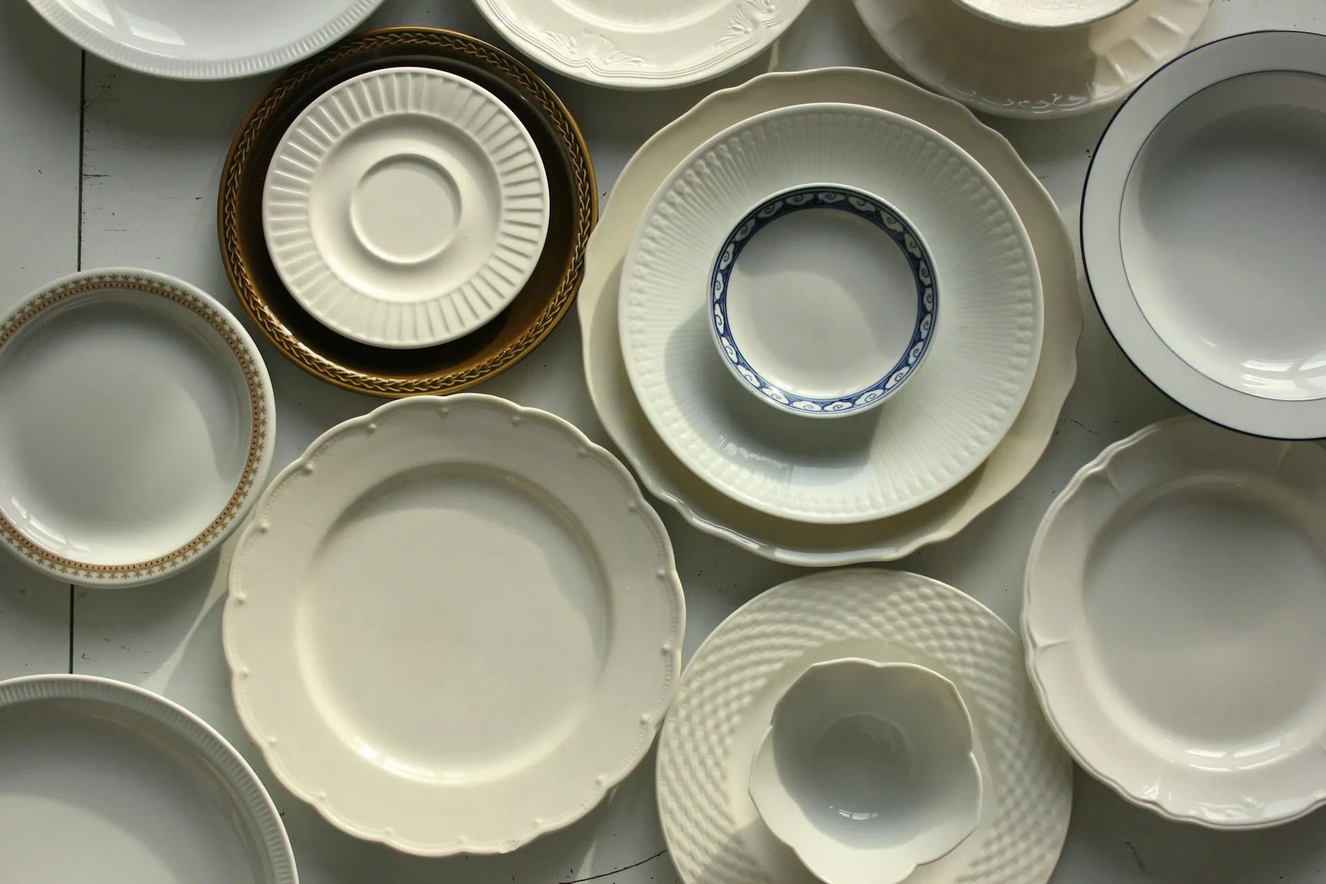 Overhead view of an empty white plate with fork, knife, spoon, mug and glass on a dark wooden table
