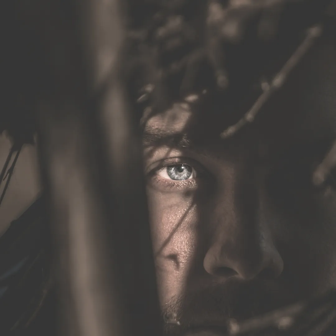 Close-up of a man's eye looking through shadows, representing the inner experience of fear and trauma