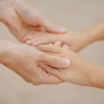 Close-up of a thumb pressing firmly into a person's forearm against a dark background