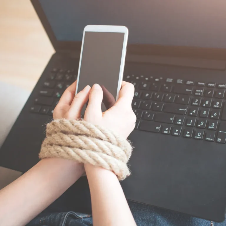 Hands tied with rope while holding a smartphone, symbolizing the psychological grip of screen addiction.