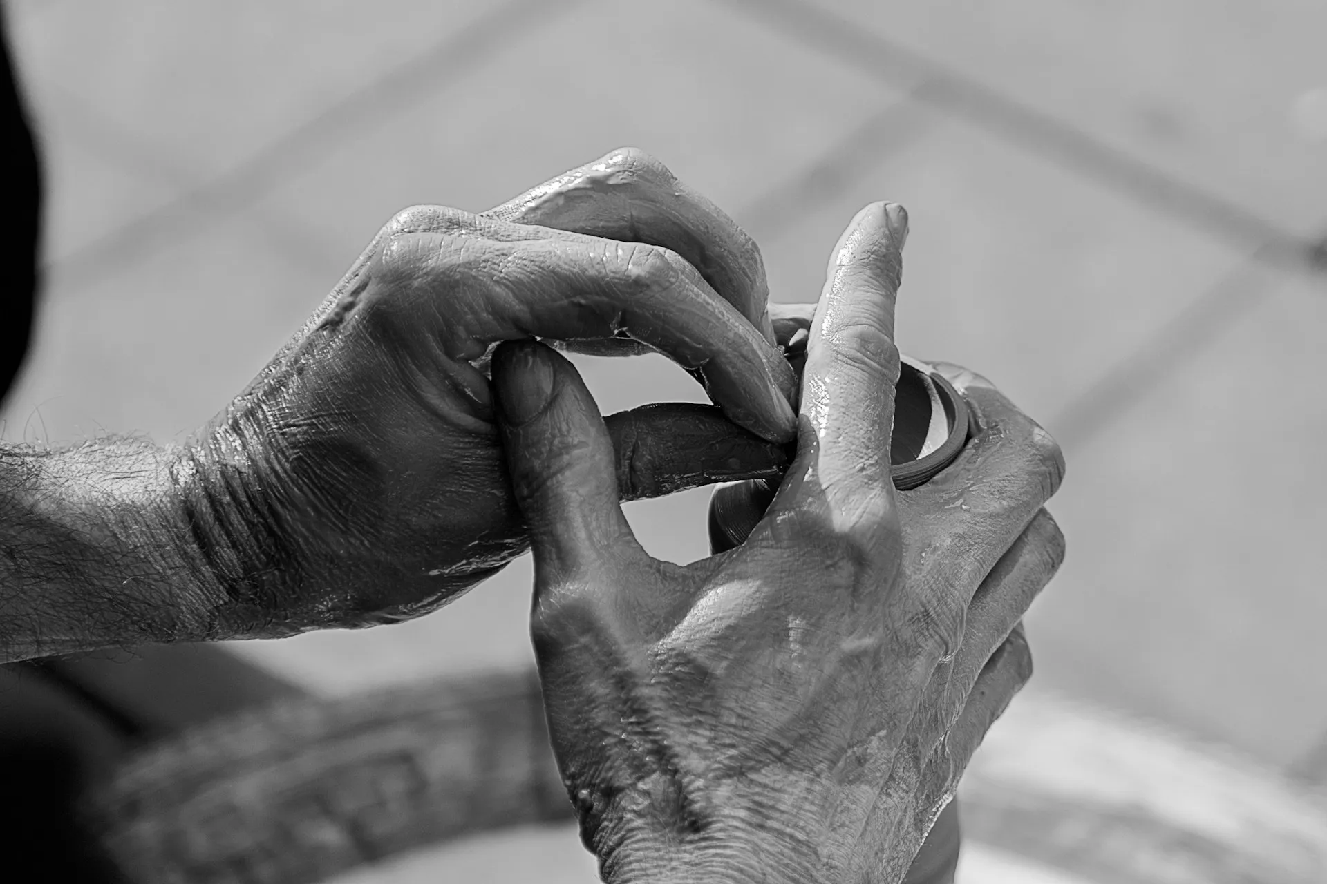 Close-up black and white photo of hands shaping wet clay on a potter's wheel