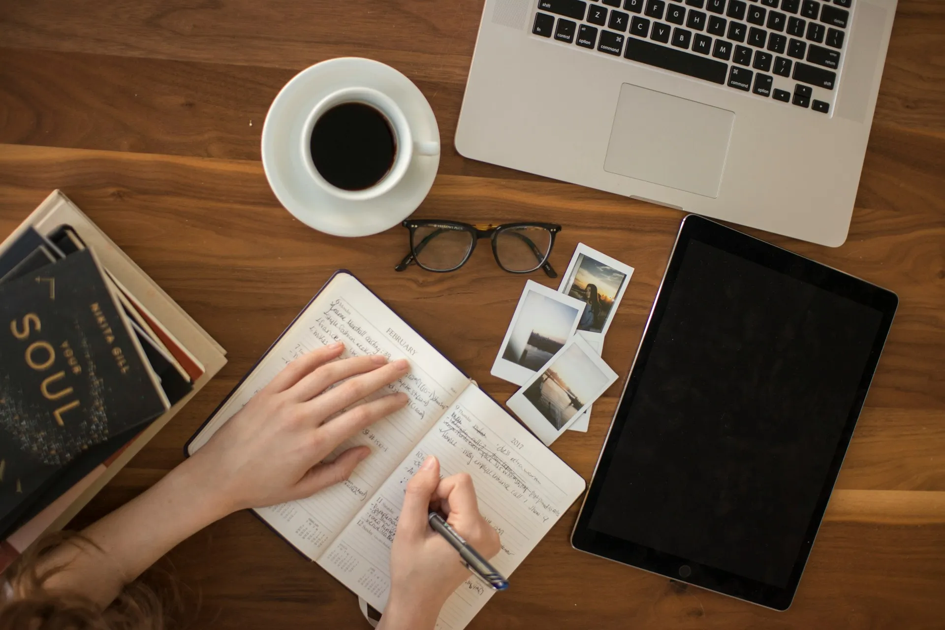 Open laptop, coffee mug, smartphone, and a handwritten notepad on a wooden desk