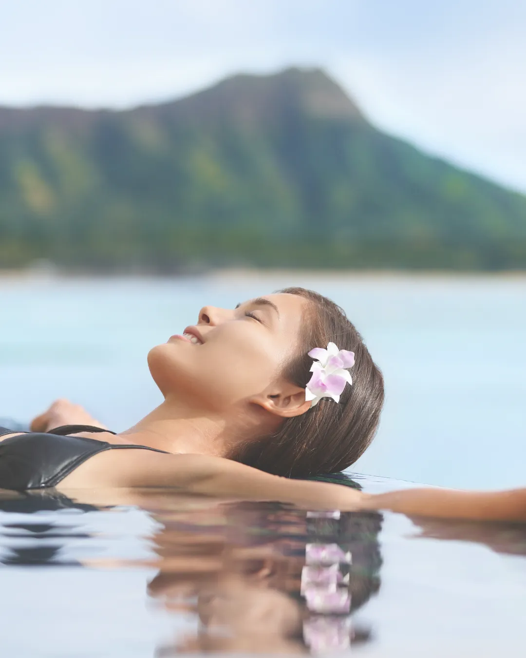 A woman enjoying a luxury wellness retreat in 2025, relaxing in an infinity pool with a serene mountain view.