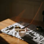 Cup of coffee on a linen runner across a wooden table in soft morning light