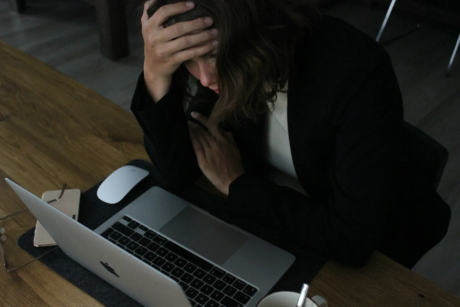Woman sitting at a laptop with her head in her hand, appearing overwhelmed