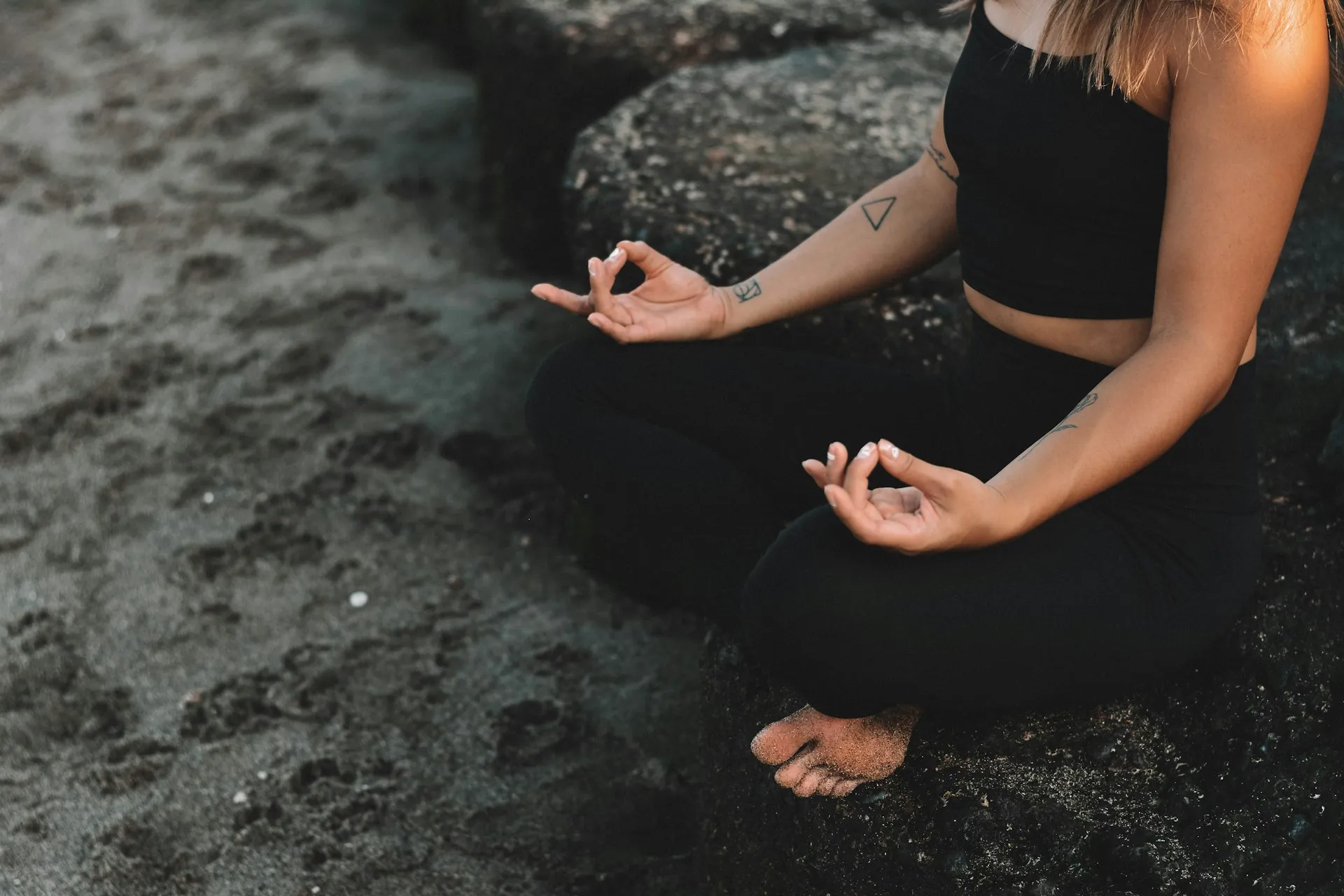 Close-up of a person practicing mindful meditation and breathwork on a rocky shore to support autonomic nervous system regulation.