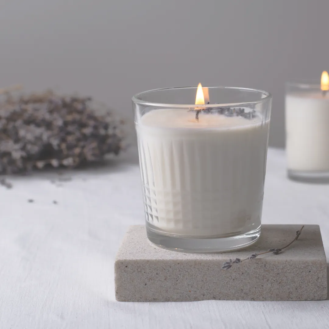 A lit candle in a glass holder with dried lavender, representing a scent-based sensory microintervention for calm and self-regulation.