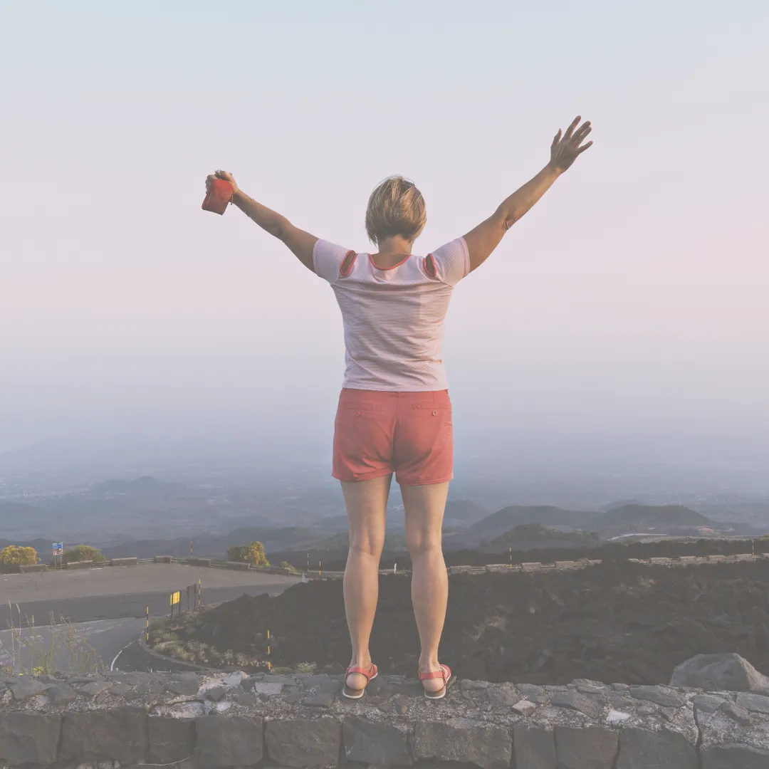 A joyful woman raising her arms, symbolizing empowerment and renewal during post-menopausal life.