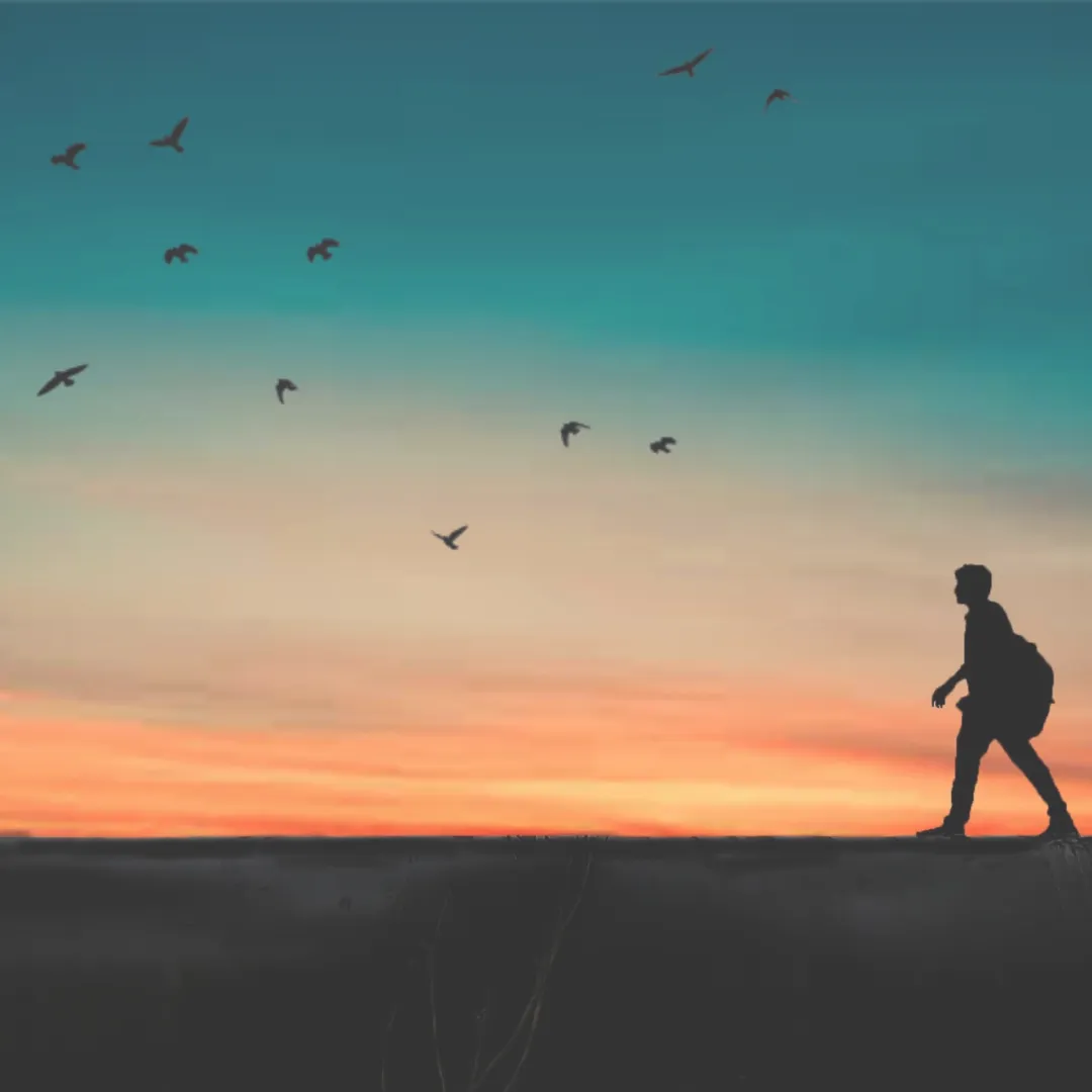 Silhouette of a person with a backpack practicing silent walking along a ridge during a colorful orange and teal sunset.