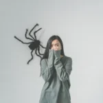 Woman startled by a large spider on the wall, representing phobia treatment using exposure therapy