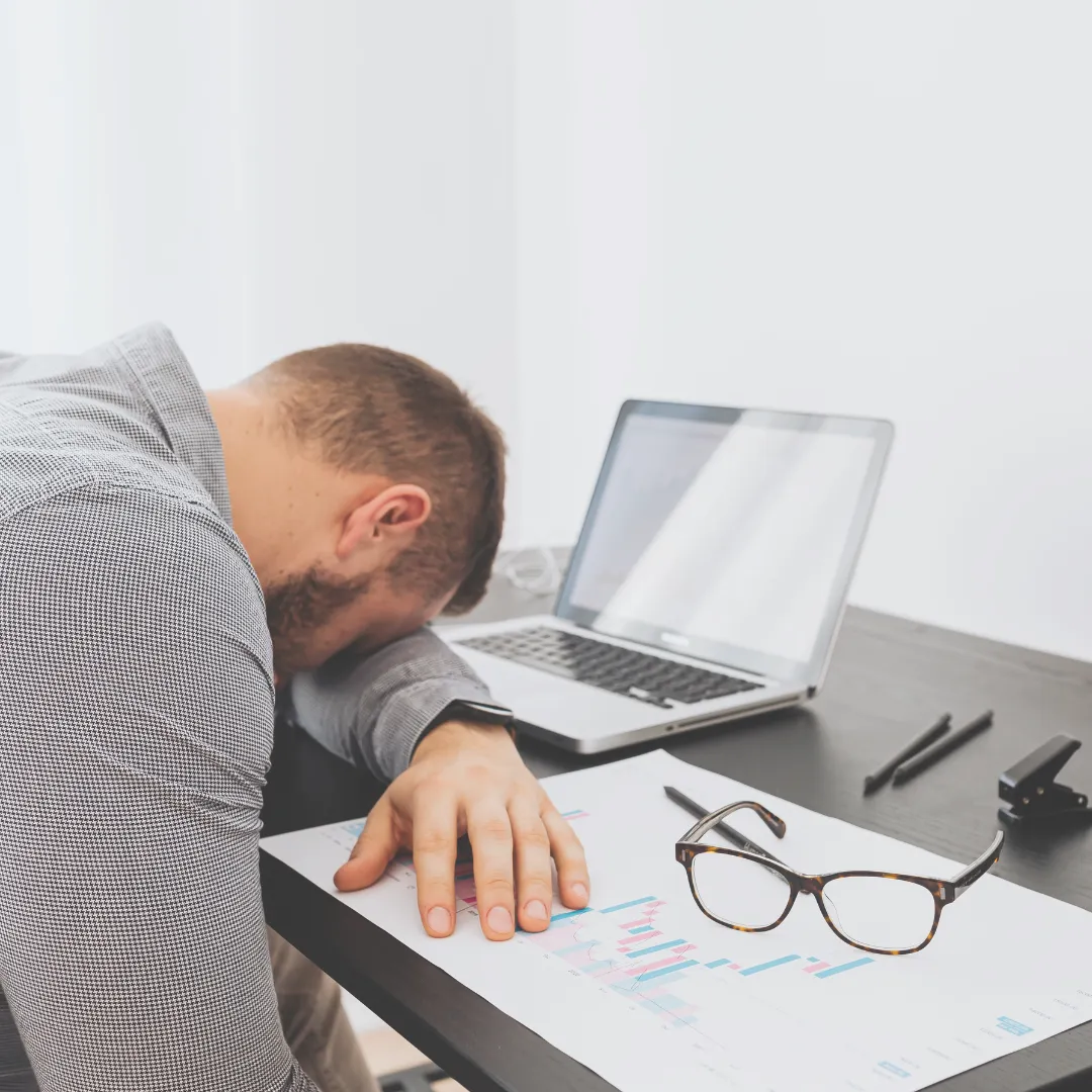 Stressed professional with head down on desk showing signs of burnout