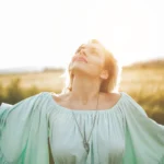 Woman embracing sunlight and summer energy while engaging in biofield therapy for vitality