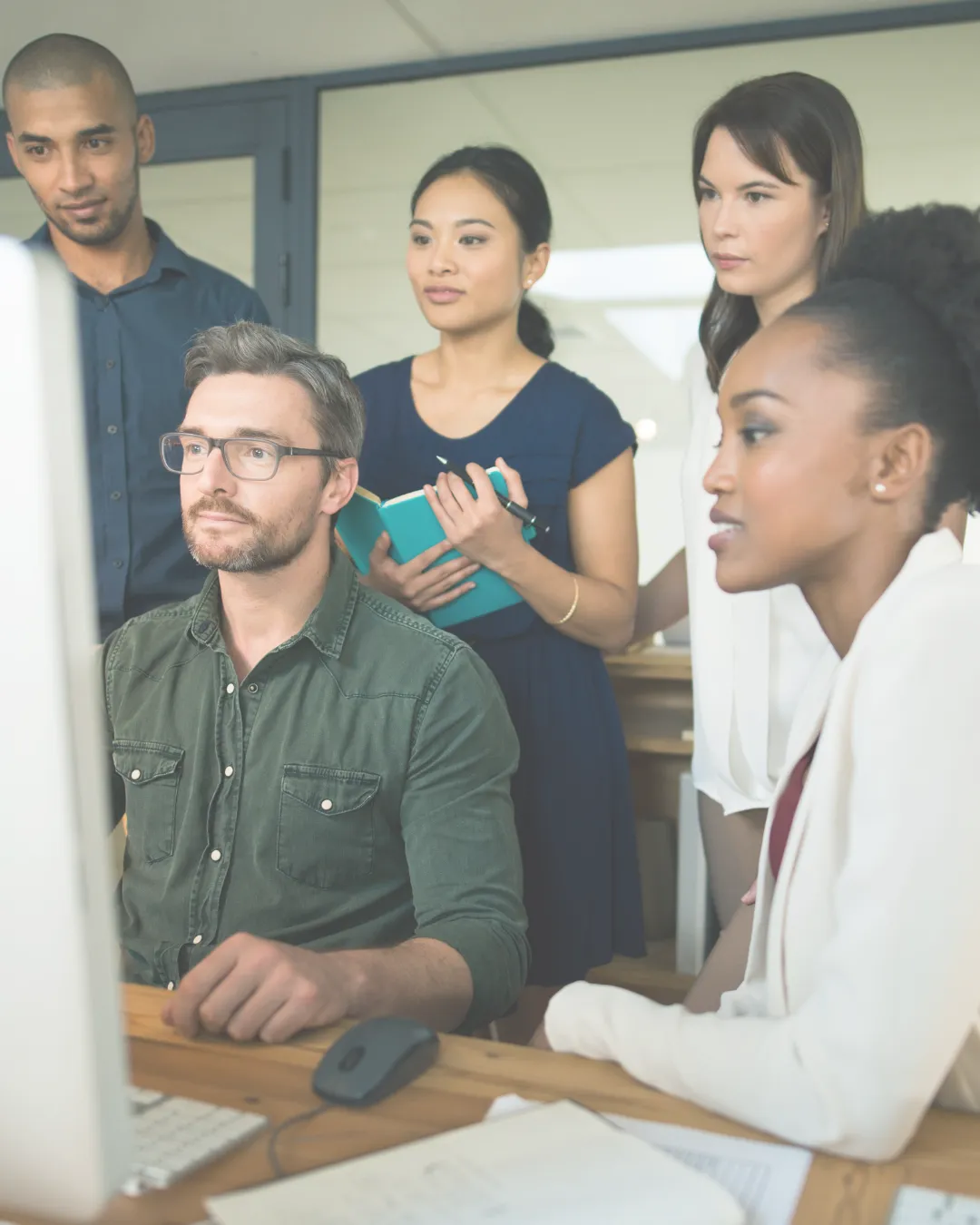 A diverse team of professionals looking at a computer screen, discussing workplace strategies for preventing burnout and improving well-being.