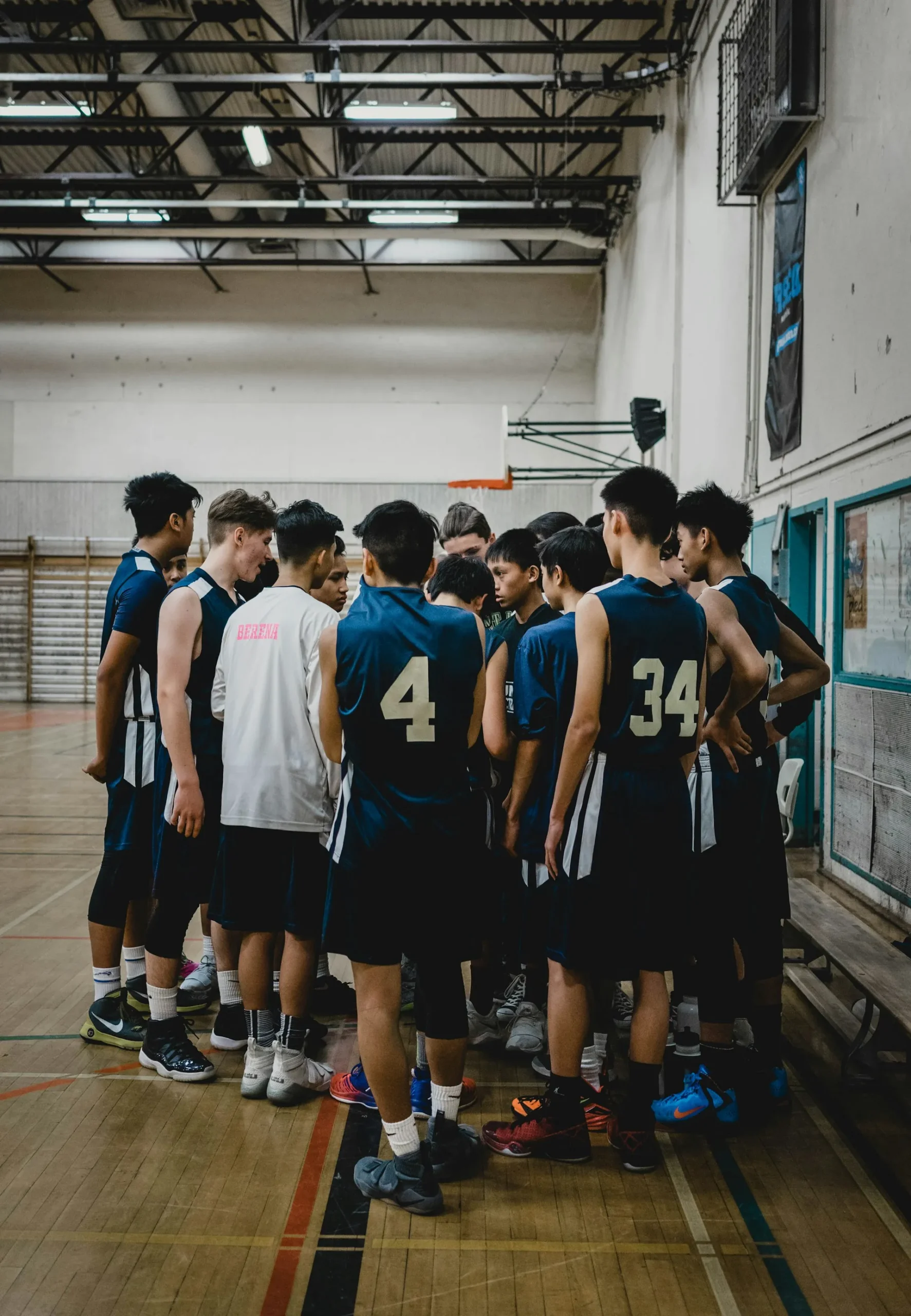 Basketball team gathered in a huddle on a gym court before play