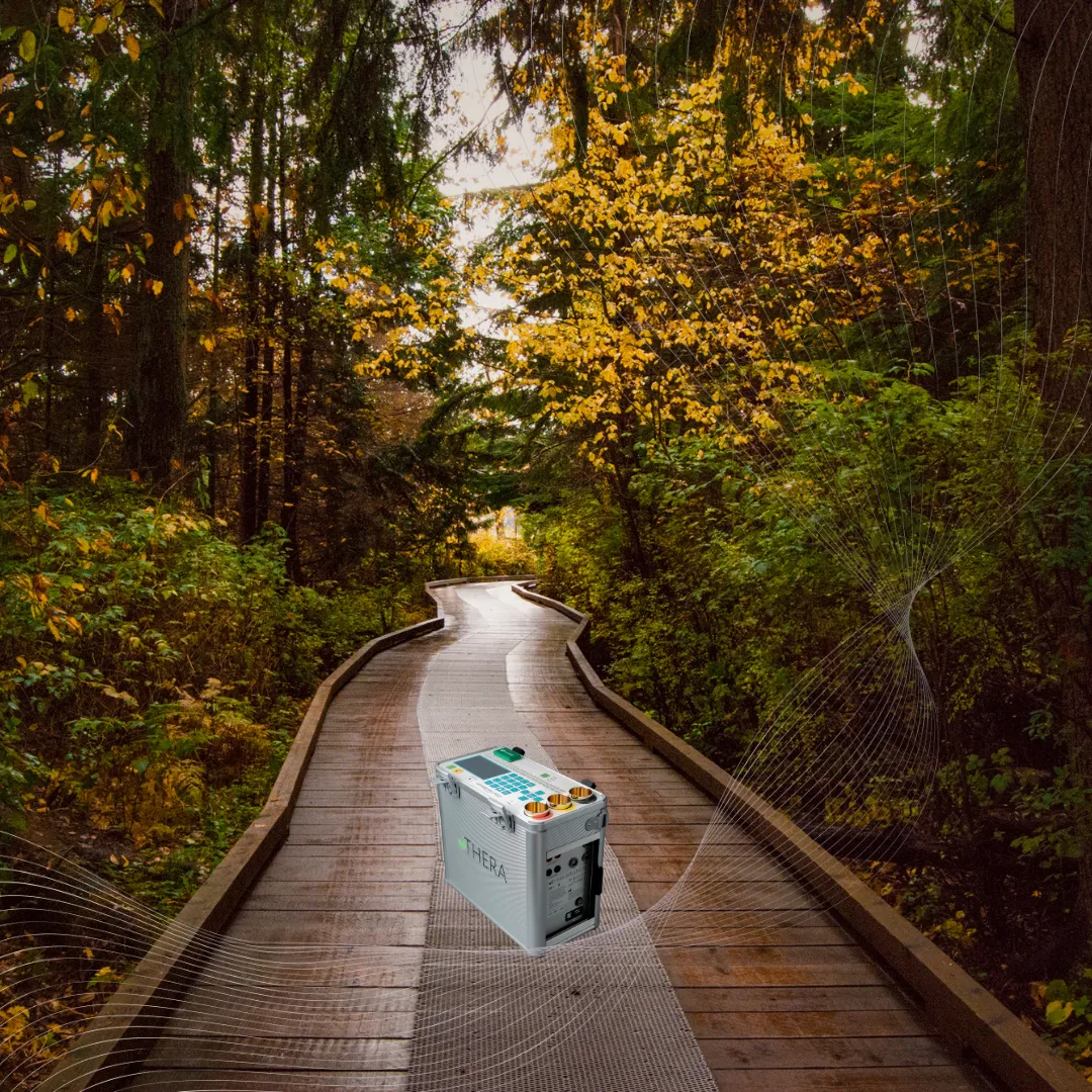 The Thera Wellness biofield device on a wooden boardwalk in an autumn forest, with subtle energy field graphics, symbolizing energetic support for seasonal transitions.