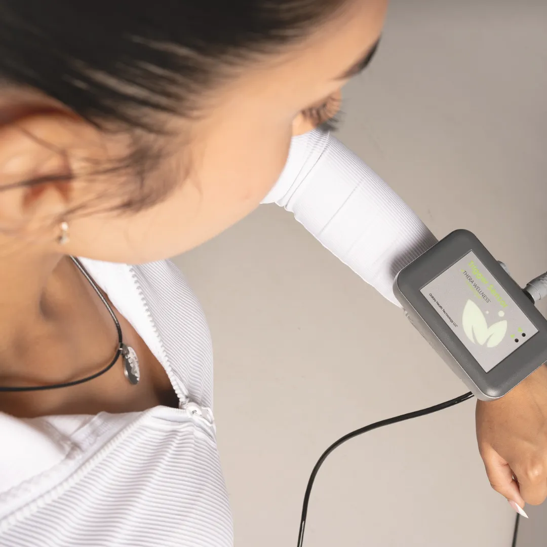 An over-the-shoulder view of a person wearing the Thera Wellness device, a wearable biofield sensor, on their wrist.