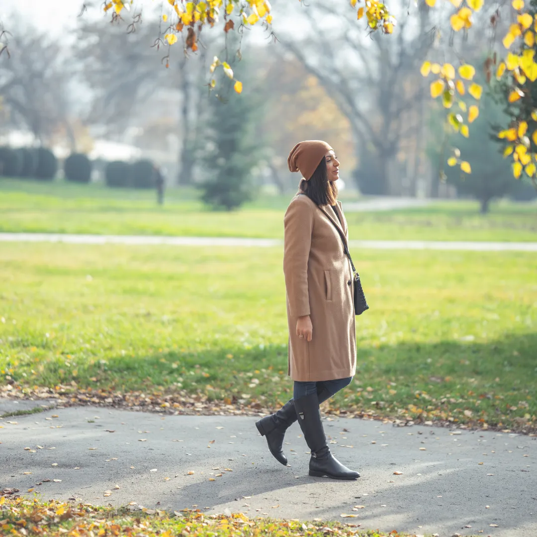 A person walking mindfully on a path in a city park during autumn, practicing an urban version of forest bathing.