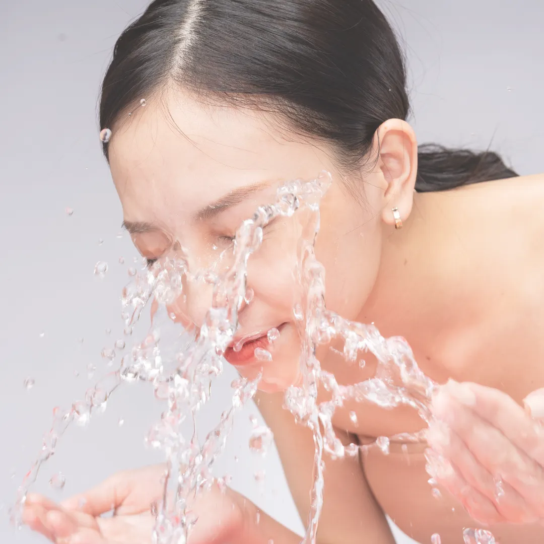 A woman splashing her face with cold water, a simple and effective technique for vagus nerve stimulation that helps regulate the gut-brain axis and calm the nervous system.