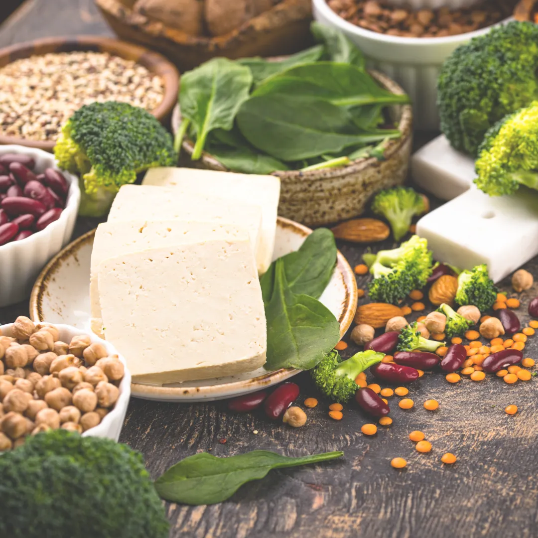 Assortment of gut-healthy vegan foods including tofu, broccoli, chickpeas, and kidney beans.