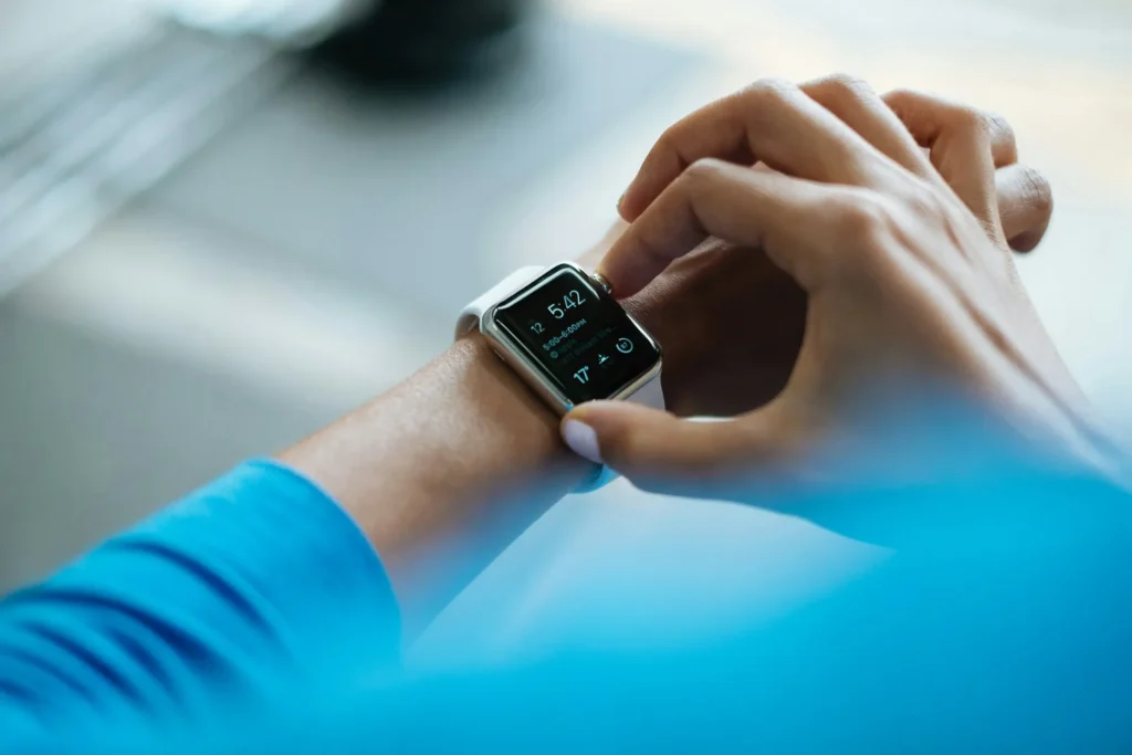Person checking a smartwatch displaying time, schedule, and temperature data on their wrist