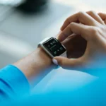 Person checking a smartwatch displaying time, schedule, and temperature data on their wrist