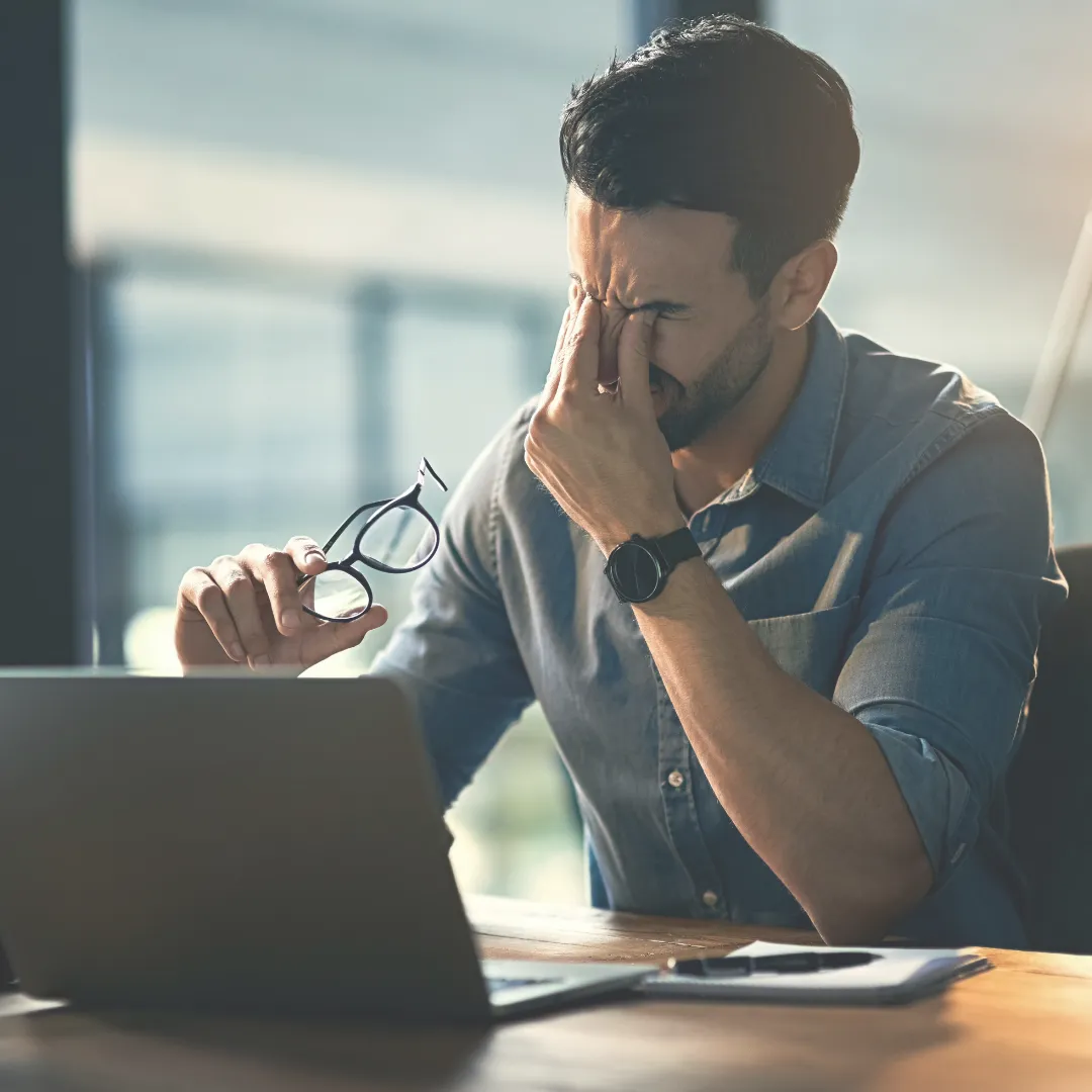 Employee experiencing workplace stress, symbolizing the need for Biofield Technology in corporate wellness programs.