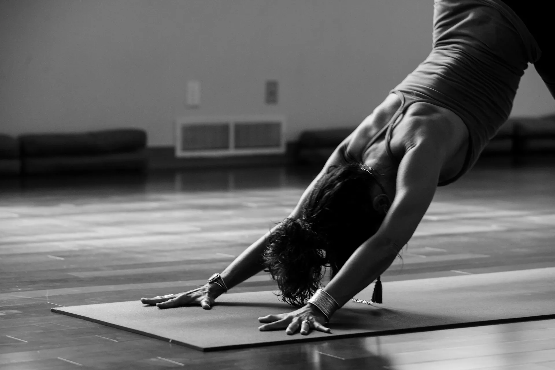 Black and white photo of a person in downward dog position on a yoga mat